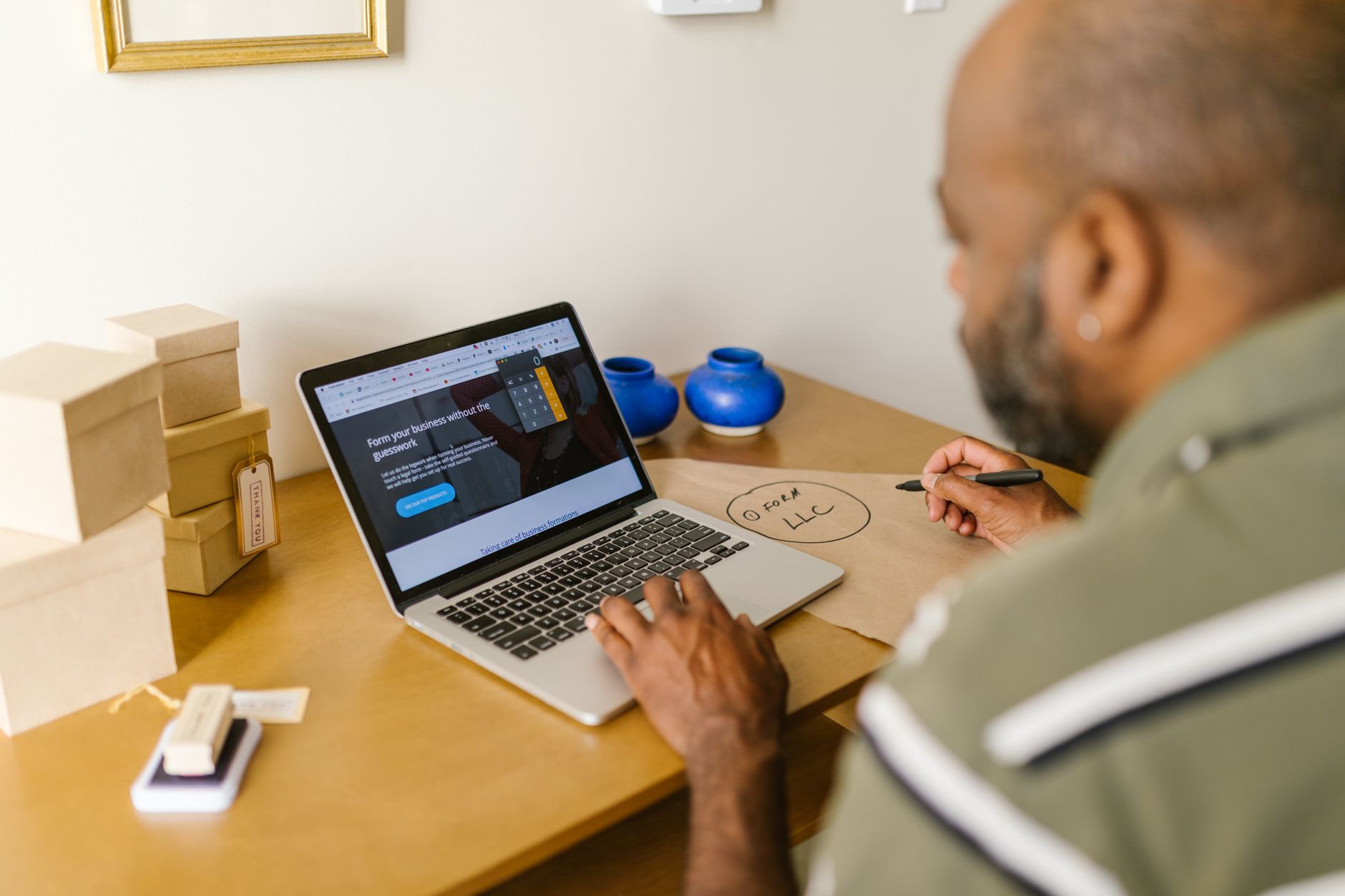 Small business owner researching his business on a laptop while taking notes
